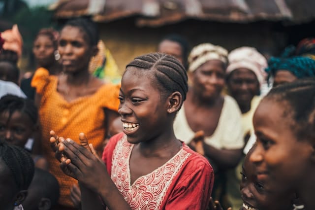A joyful child surrounded by her community during foundation outreach